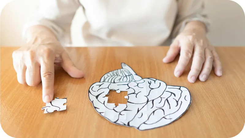 Handen van een oudere vrouw leggen een puzzelstuk in een papieren brein